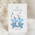Coastal Blues Lilac Ear Studs Set — three pairs of lilac-shaped studs in white, sky blue, and slate blue on a Dimenciel branded card