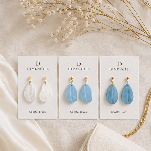Coastal Blues Petal Drop Earrings — three pairs in Sea Salt, Mist Blue, and Slate Blue on Dimenciel branded cards styled with a cream skirt and blue cardigan